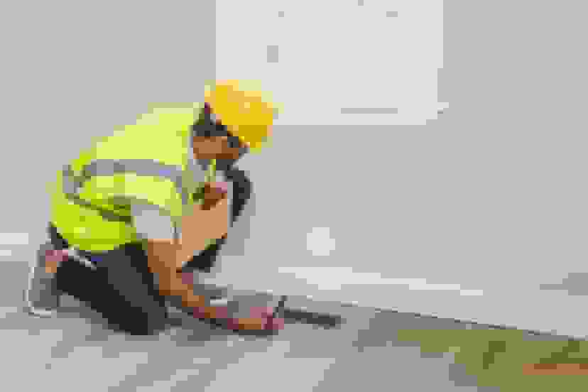 HVAC professional in a hardhat inspecting a vent